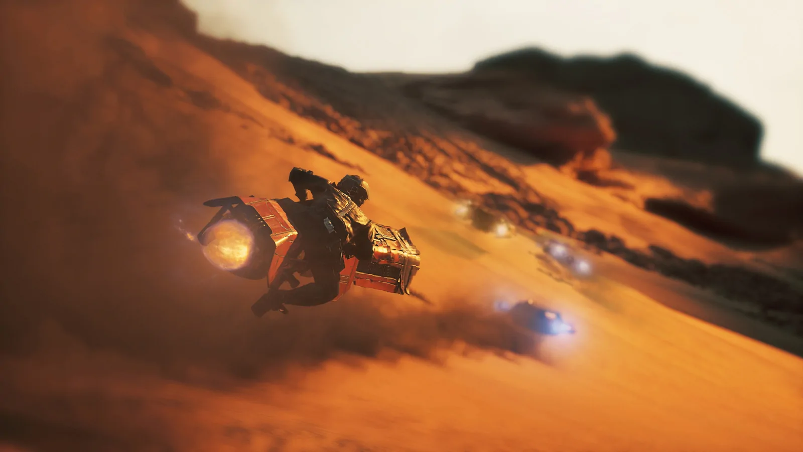 A racer streaking low across orange desert dunes with a rival close behind